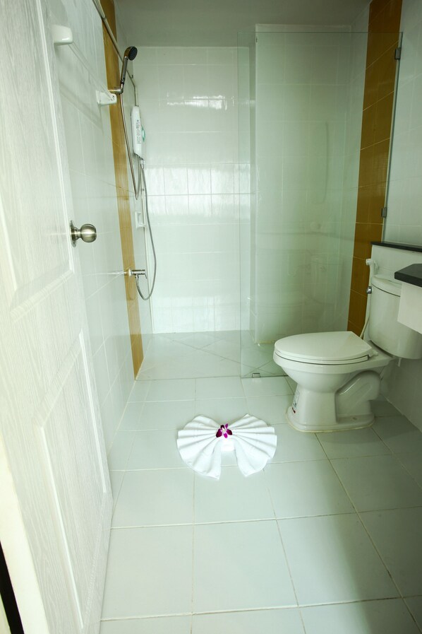 Un baño con inodoro, ducha y una toalla en el suelo.