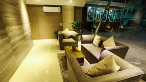 A modern living room with a sofa set, a coffee table, and a potted plant. - Patt Serviced Apartments (Chonburi)
