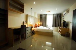 Una habitación de hotel moderna con cama, escritorio, silla y televisor.
