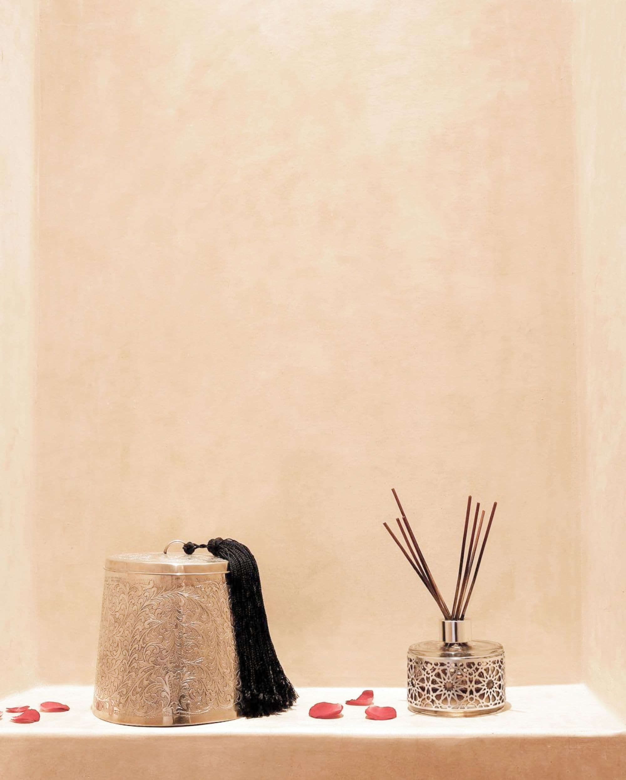 Pared beige con textura y dos recipientes decorativos sobre un estante blanco.
