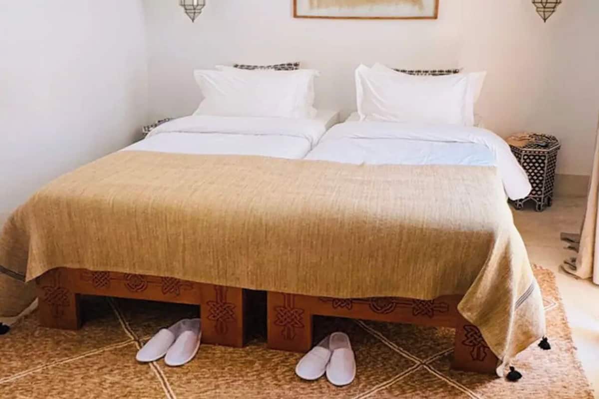 A bed with a beige bedspread, two white pillows, and a star decoration on the wall.