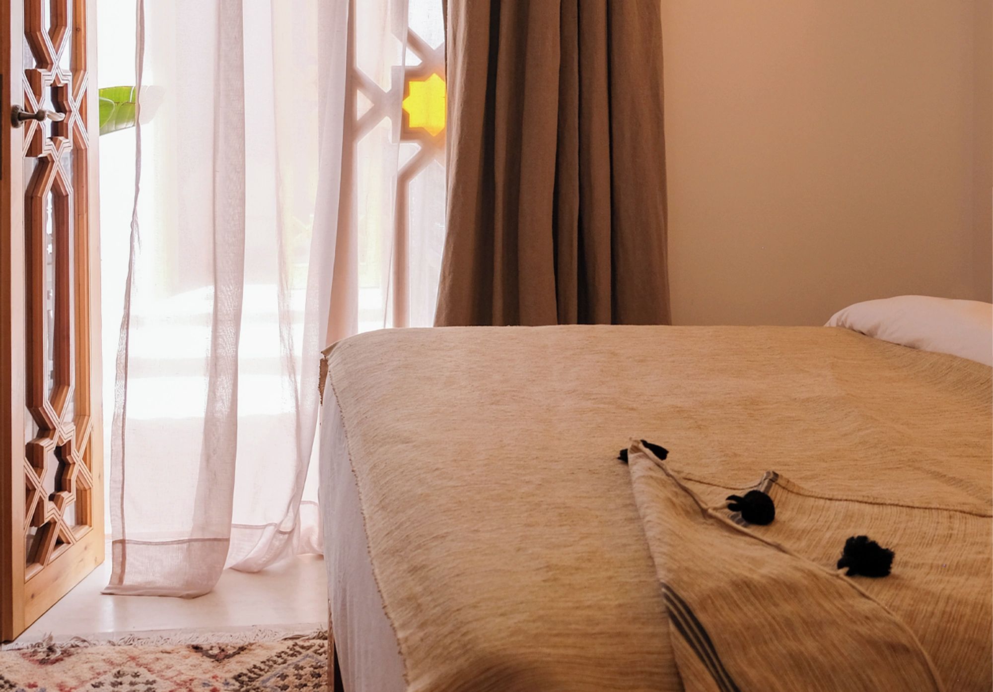 A hotel room with a bed, curtains, and a window with a view.
