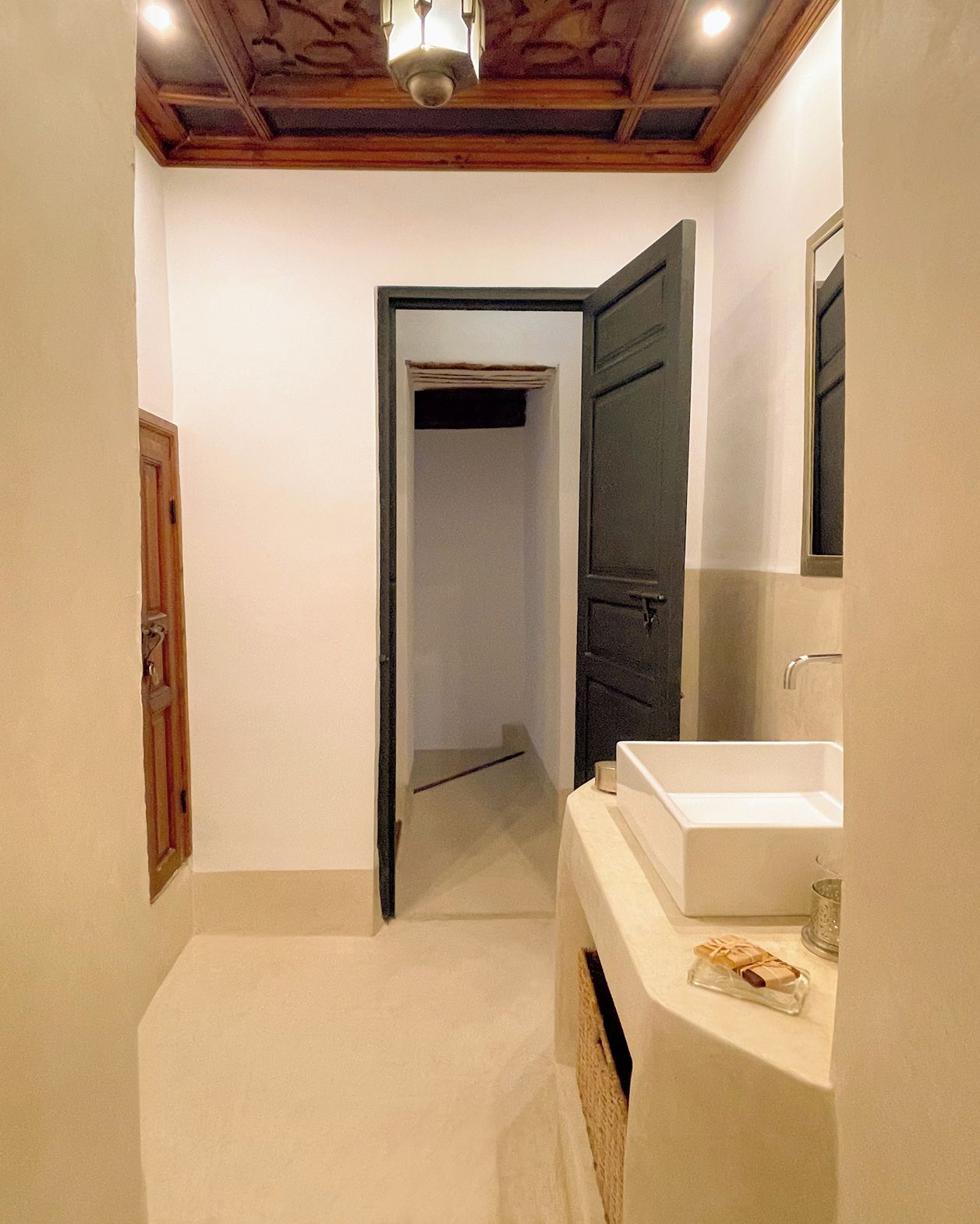 A bathroom with a white sink, a mirror, and a wooden ceiling.