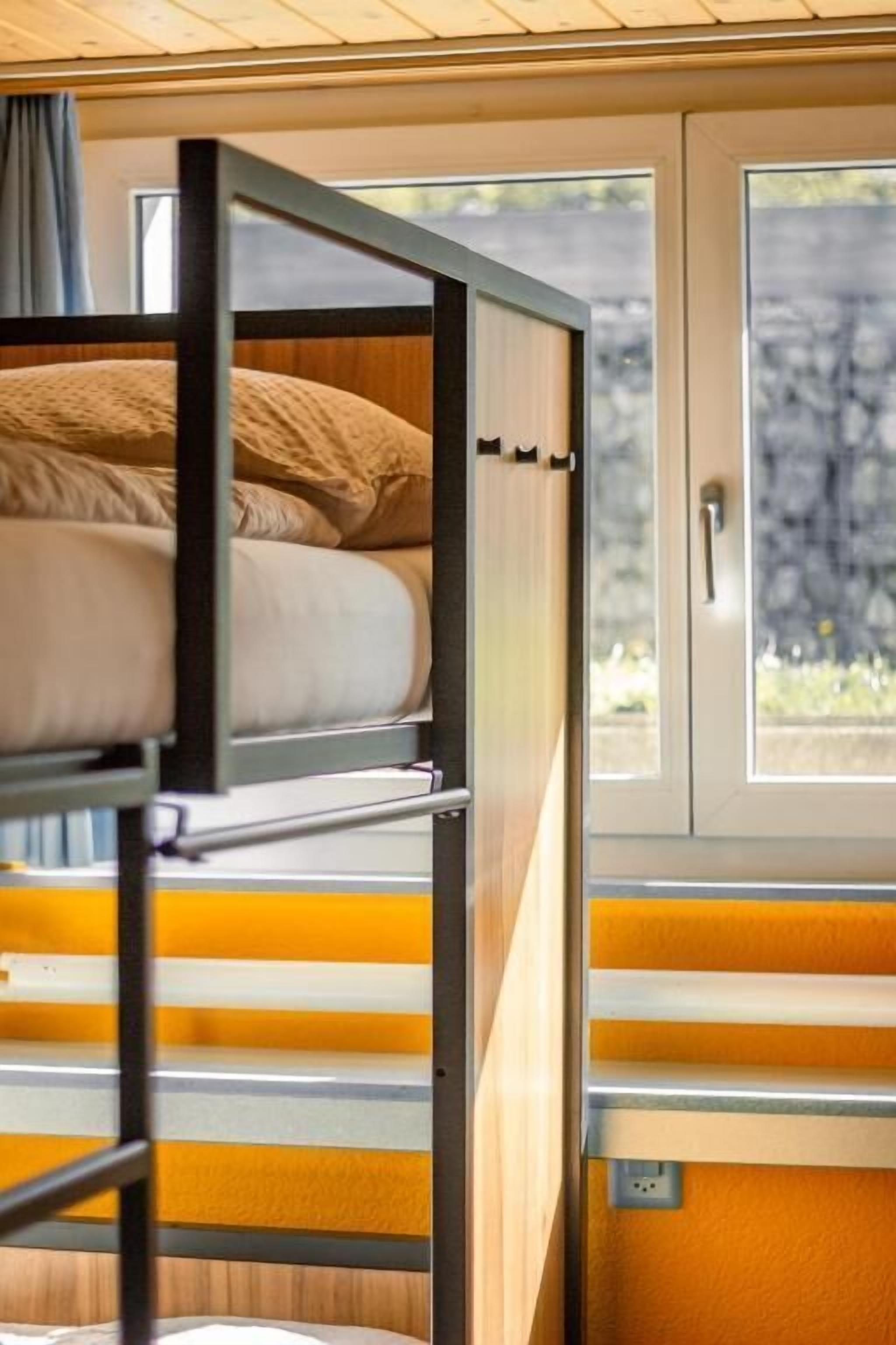 Ein Stockbett mit Blick aus dem Fenster, einer Tür und einer Steckdose.