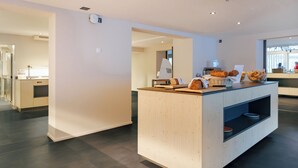A modern reception area with a wooden counter, a seating area, and a view of the street. - Eiger Lodge Easy (Grindelwald)
