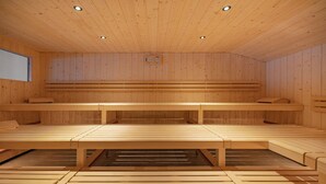 A sauna with wooden benches and a central table, wooden walls, and ceiling lights. - Eiger Lodge Easy (Grindelwald)