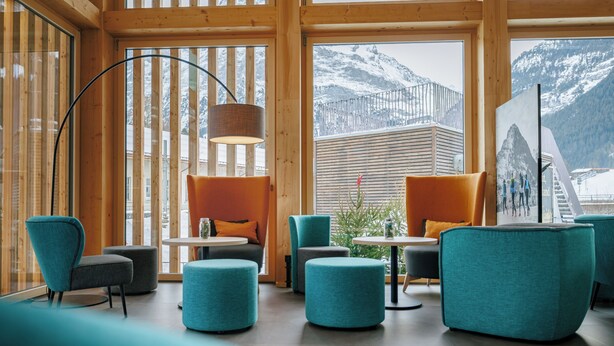 A modern interior with wooden walls, large windows, and a view of snow-capped mountains. - Eiger Lodge Easy (Grindelwald)