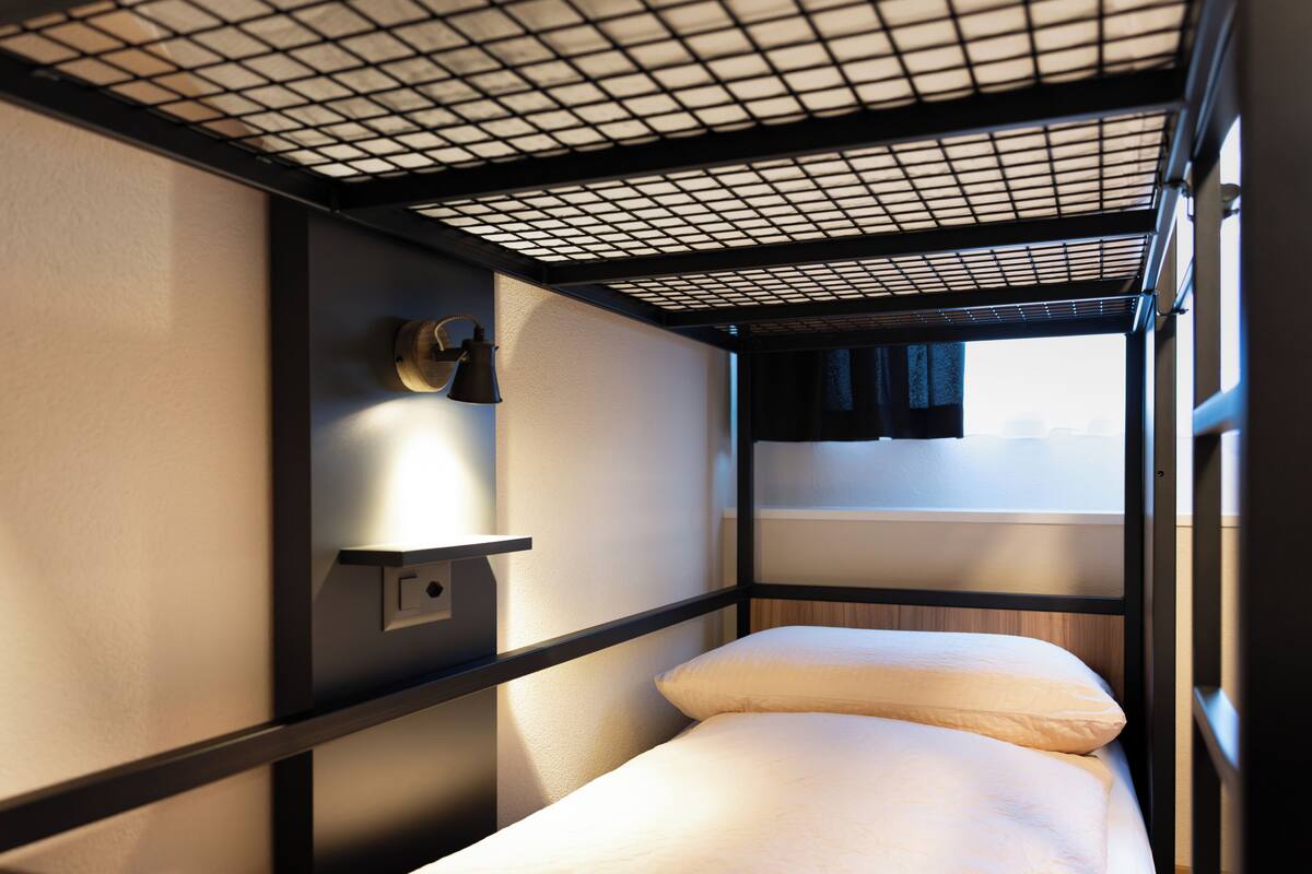 A bunk bed with a headboard and a shelf with a lamp.