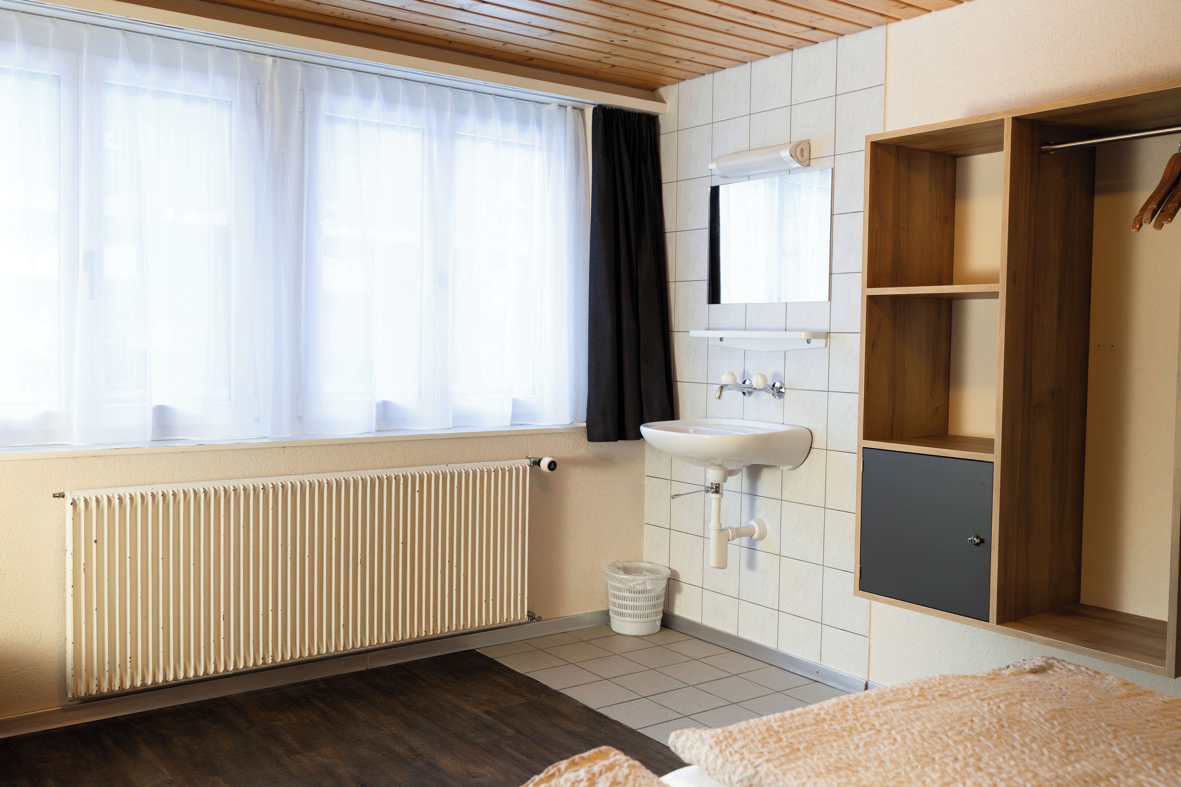 Une salle de bain moderne avec une fenêtre, un radiateur, un lavabo et des étagères en bois.