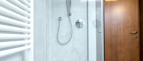 A glass-enclosed shower with a modern design, a wooden door, and a tiled floor.