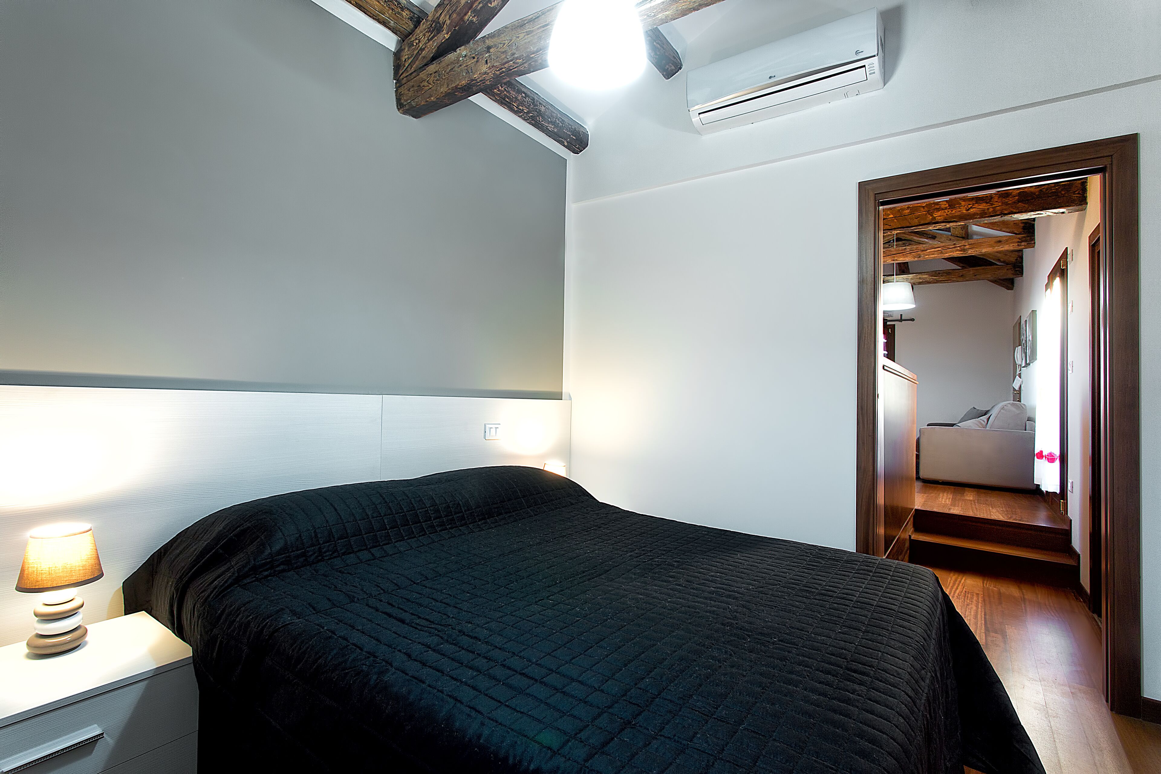 Een slaapkamer met een bed, een bedlampje en een airconditioning.