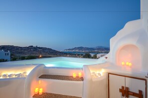 A rooftop pool with a view of a city and mountains at dusk. - Naxos Euphoria Suites (Naxos)