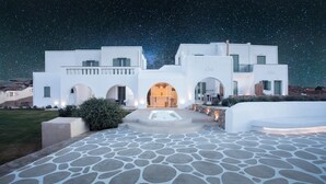 A white building with multiple arches and a stone-paved courtyard.
