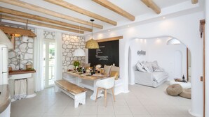 A modern interior with a dining area, a sofa, and a stone wall.