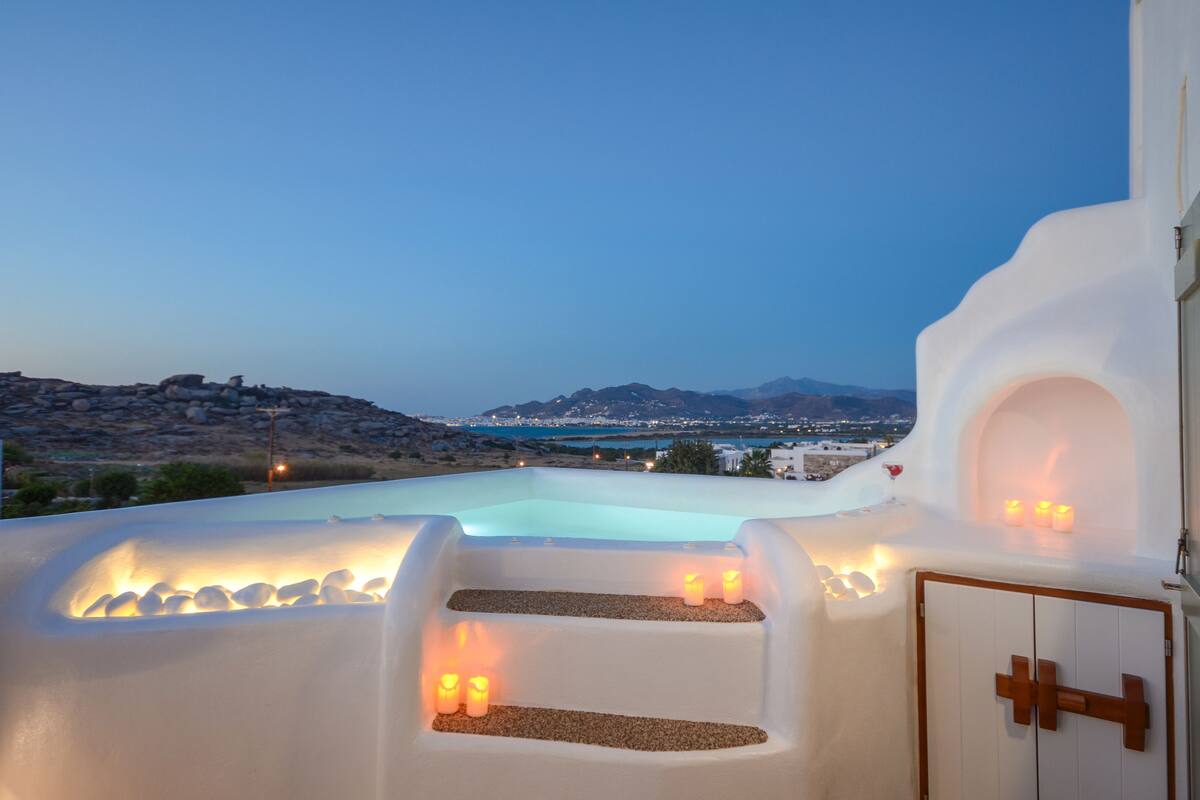 Zona de piscina con escalones y velas, con vistas a un paisaje pintoresco.