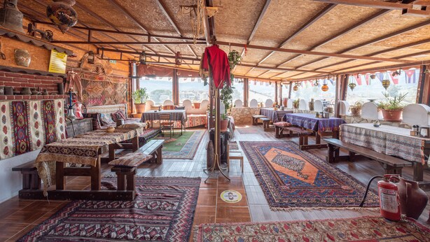 Une auberge traditionnelle avec des poutres en bois, des tapis à motifs et un décor rustique.
