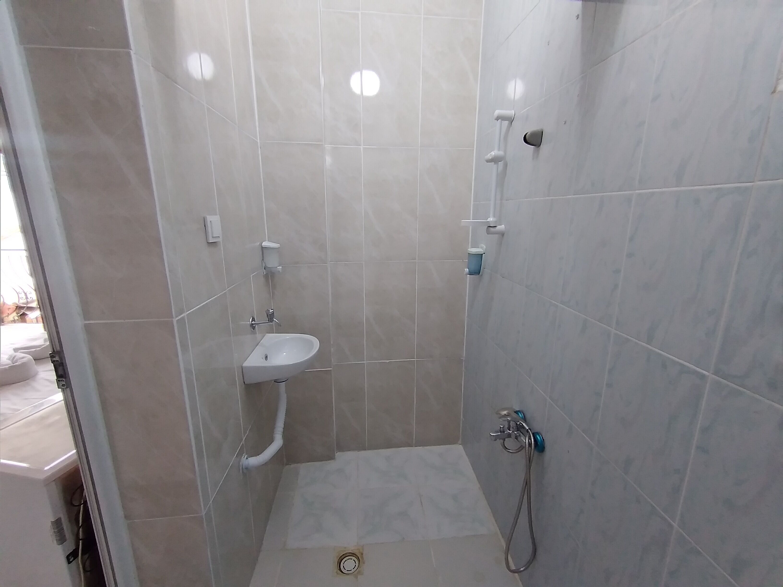 A small, tiled bathroom with a sink, a shower, and a toilet.