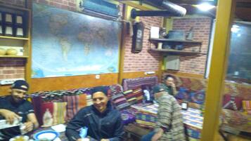 Un restaurante con paredes de ladrillo, un gran mapa mundial y mesas con mantas.