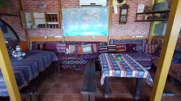 Una habitación rústica con pared de ladrillo, un mapa grande, un banco de madera y una mesa con manteles estampados.