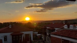 Un coucher de soleil sur un quartier résidentiel, avec des toits recouverts de tuiles rouges et quelques bâtiments.