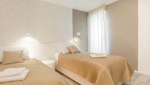 A hotel room with two beds, beige bedding, a nightstand, and a window with curtains. - Guest House Teatrin Split (Split)