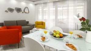 A modern dining area with a white table set for breakfast, including croissants, fruits, and orange juice. - Guest House Teatrin Split (Split)