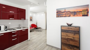 A modern kitchen with red cabinets, a white countertop, and a dining area with a red chair and a small table. - Guest House Teatrin Split (Split)