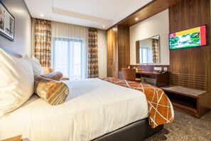 A hotel room with a large bed, a desk, a television, and a window with curtains. - City Lodge Hotel Newtown (Johannesburg)