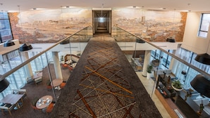 A modern interior with a central staircase, glass railings, and a cityscape mural on the walls.