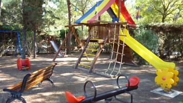 Children can play on the climbing structure, slide, seesaw, and merry-go-round in this park playground.