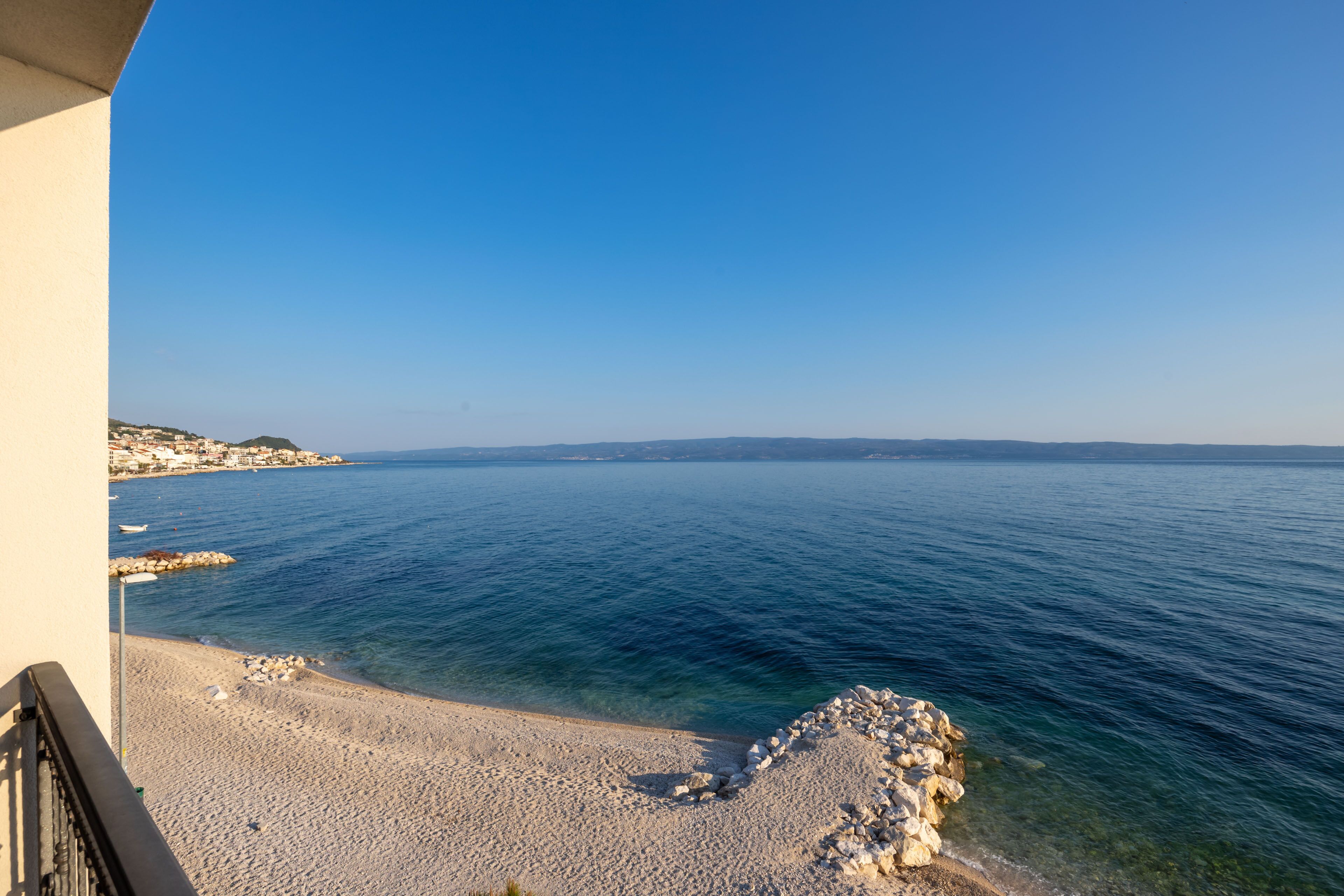 Une vue sur la côte, avec un ciel dégagé, une plage de galets et une côte rocheuse.
