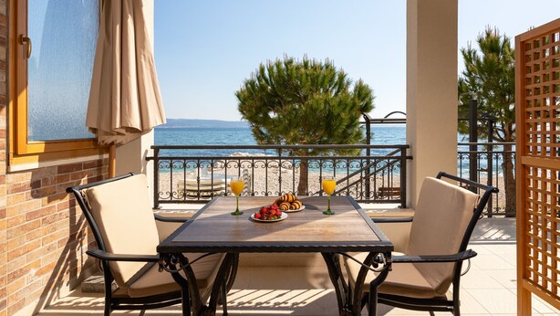 Un balcon avec une table, des chaises et une vue sur la mer.