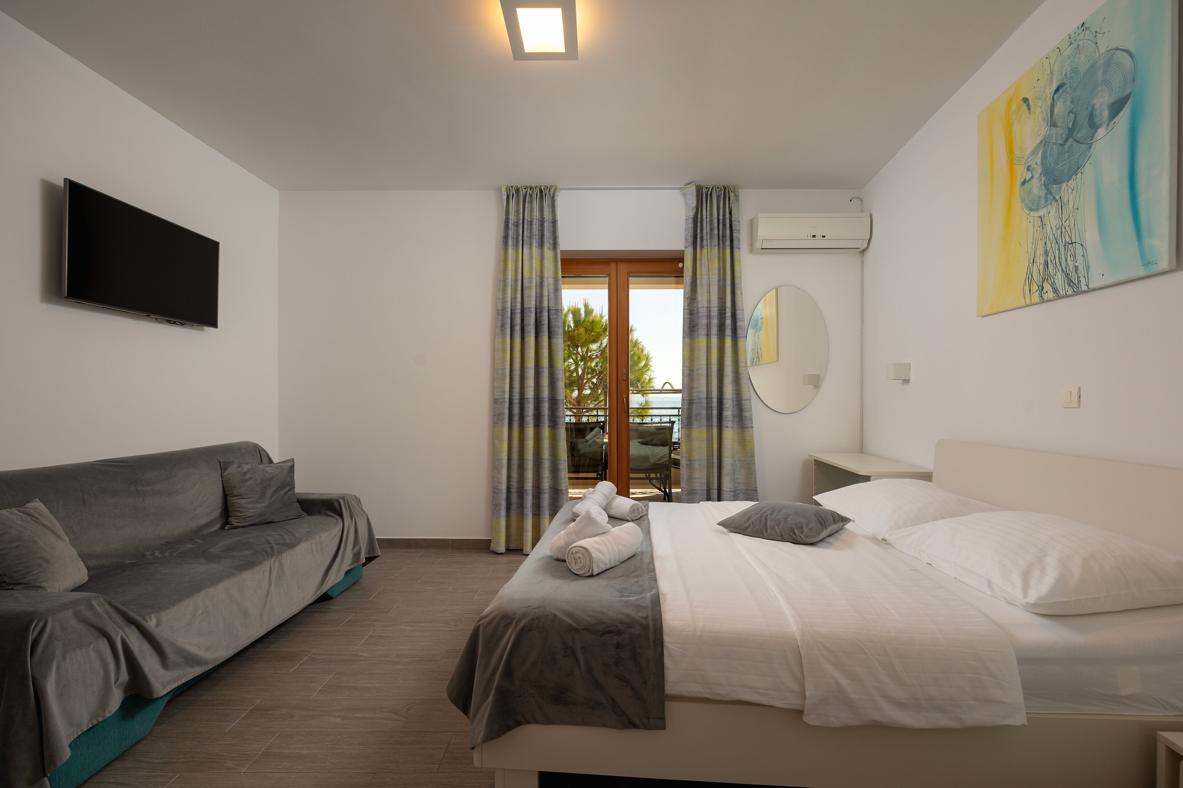 Une chambre d’hôtel moderne équipée d’un lit, d’un canapé, d’une télévision et d’un tableau.