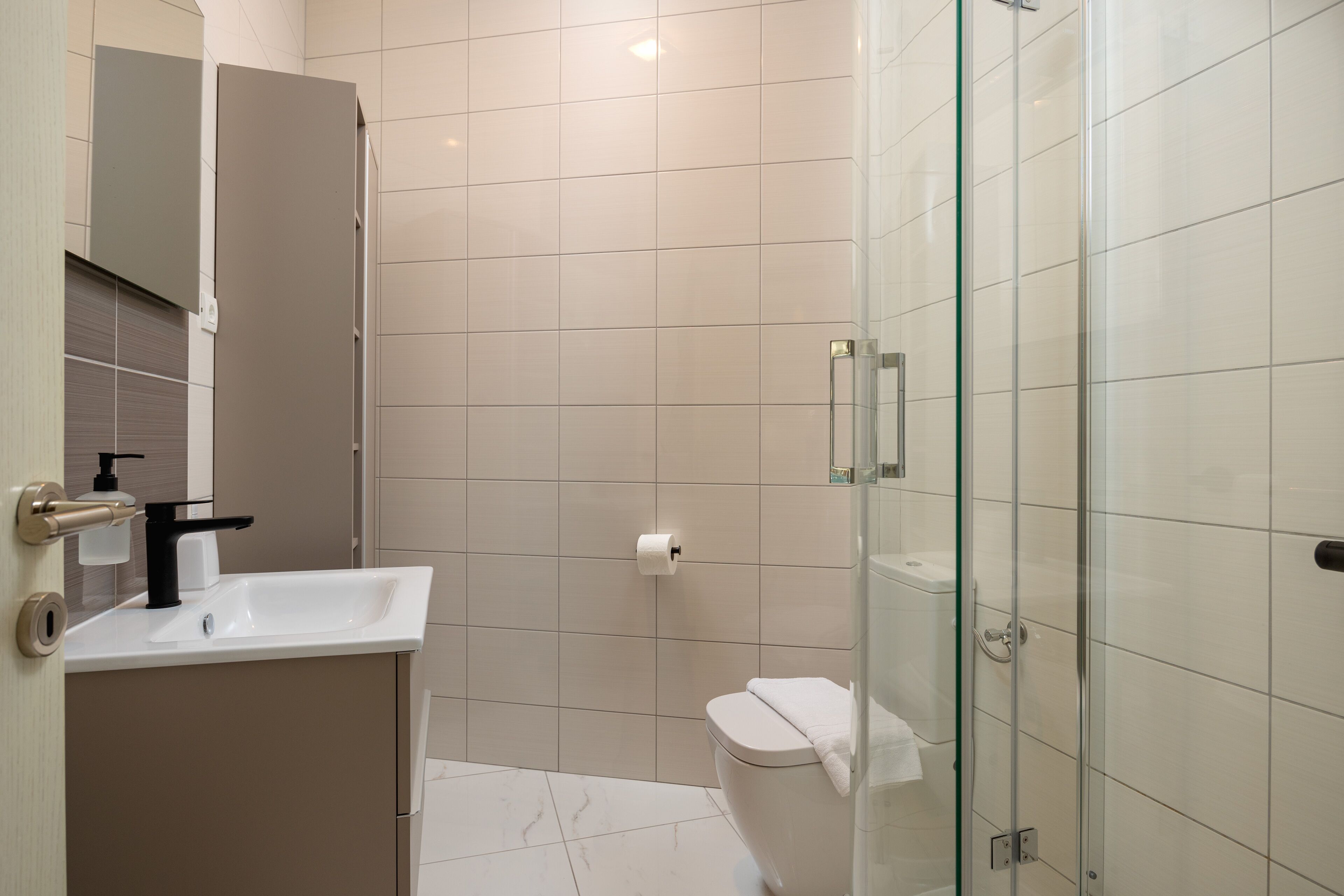 A modern bathroom with a glass shower enclosure, a white sink, and a toilet.