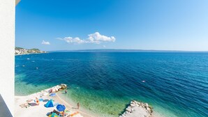 Une vue sur la côte, avec une eau bleue et limpide, une plage de sable et quelques parasols.