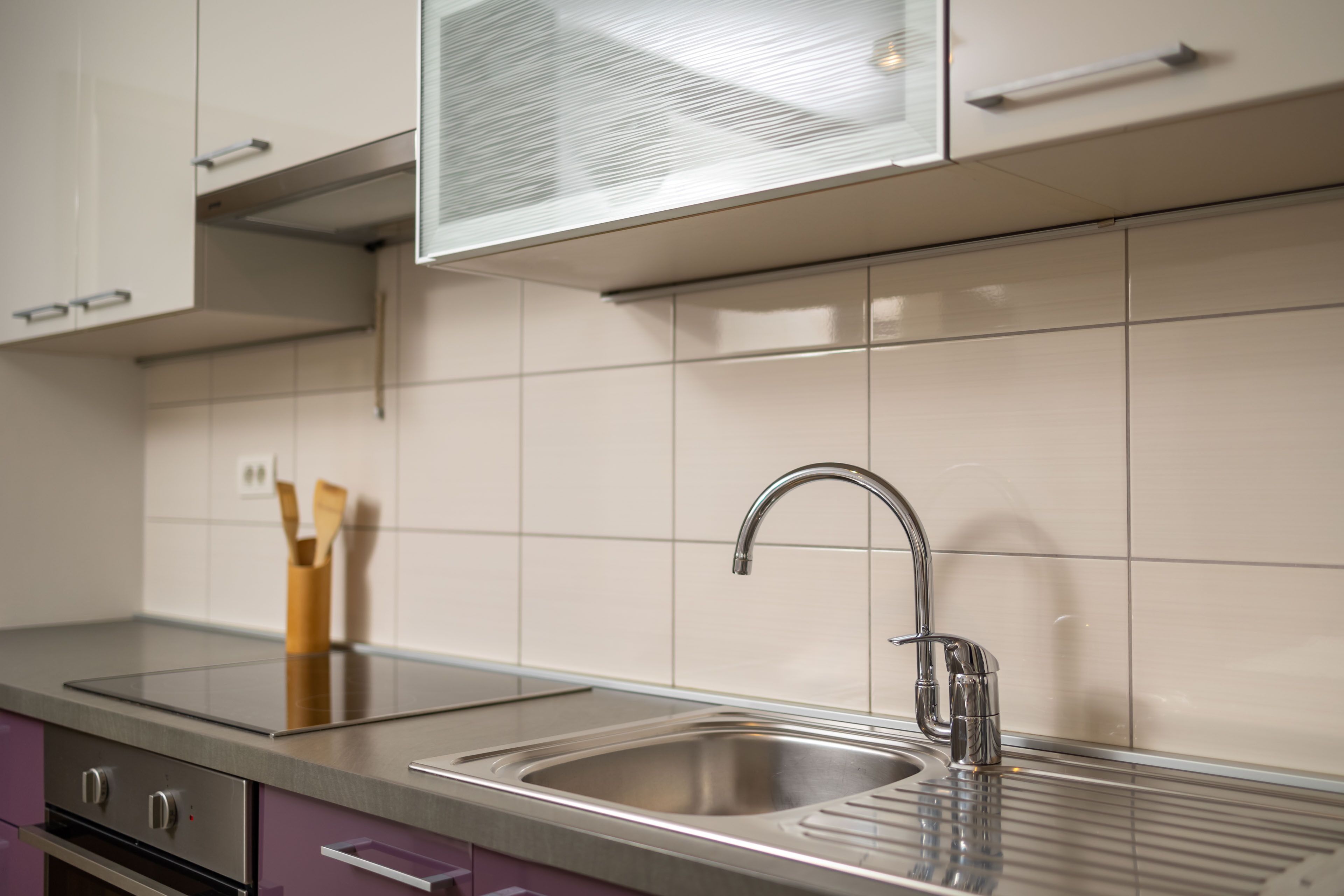 A modern kitchen with a stainless steel sink, a built-in oven, and a microwave above the counter.