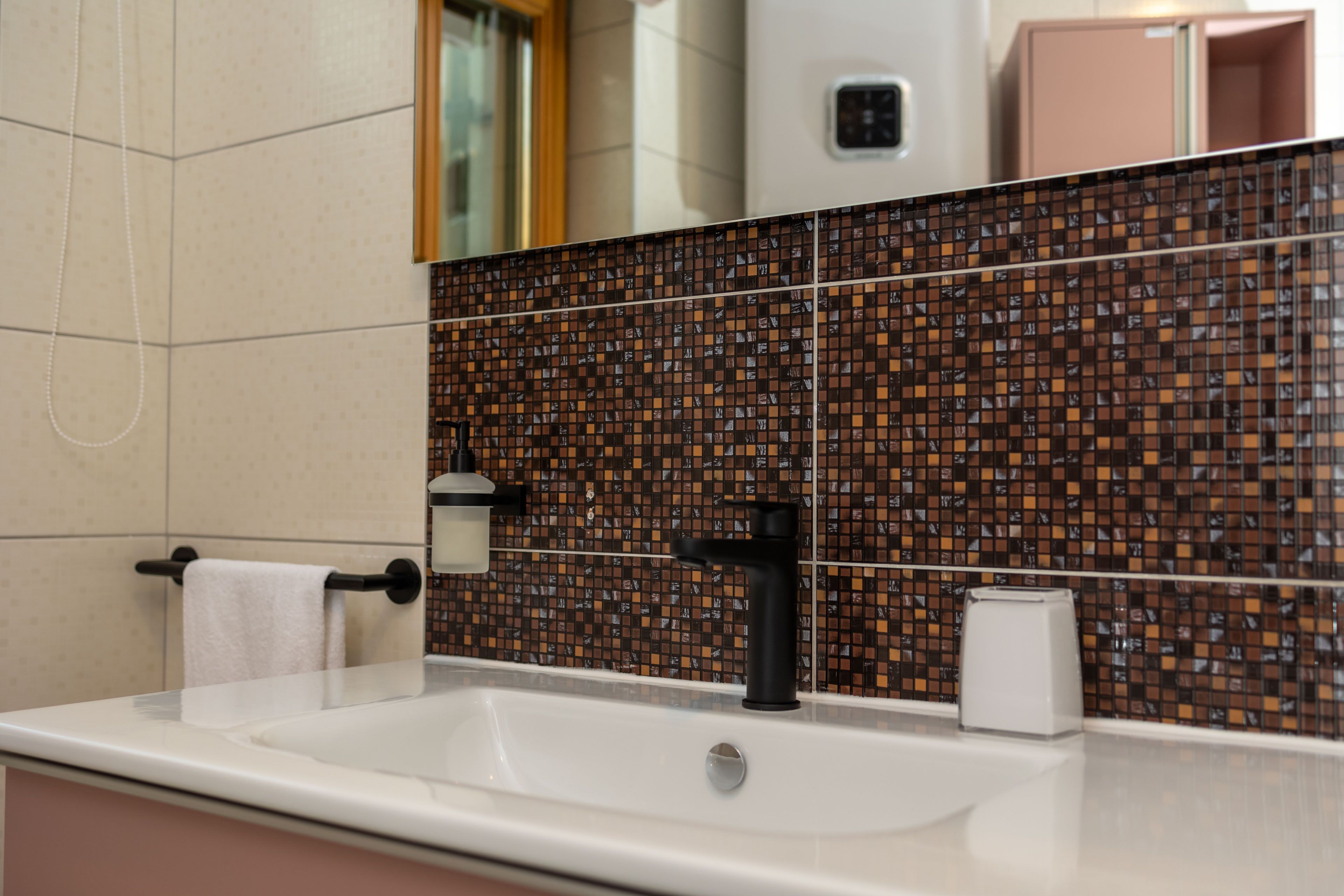 A bathroom with a white sink, black faucet, and a tiled backsplash.