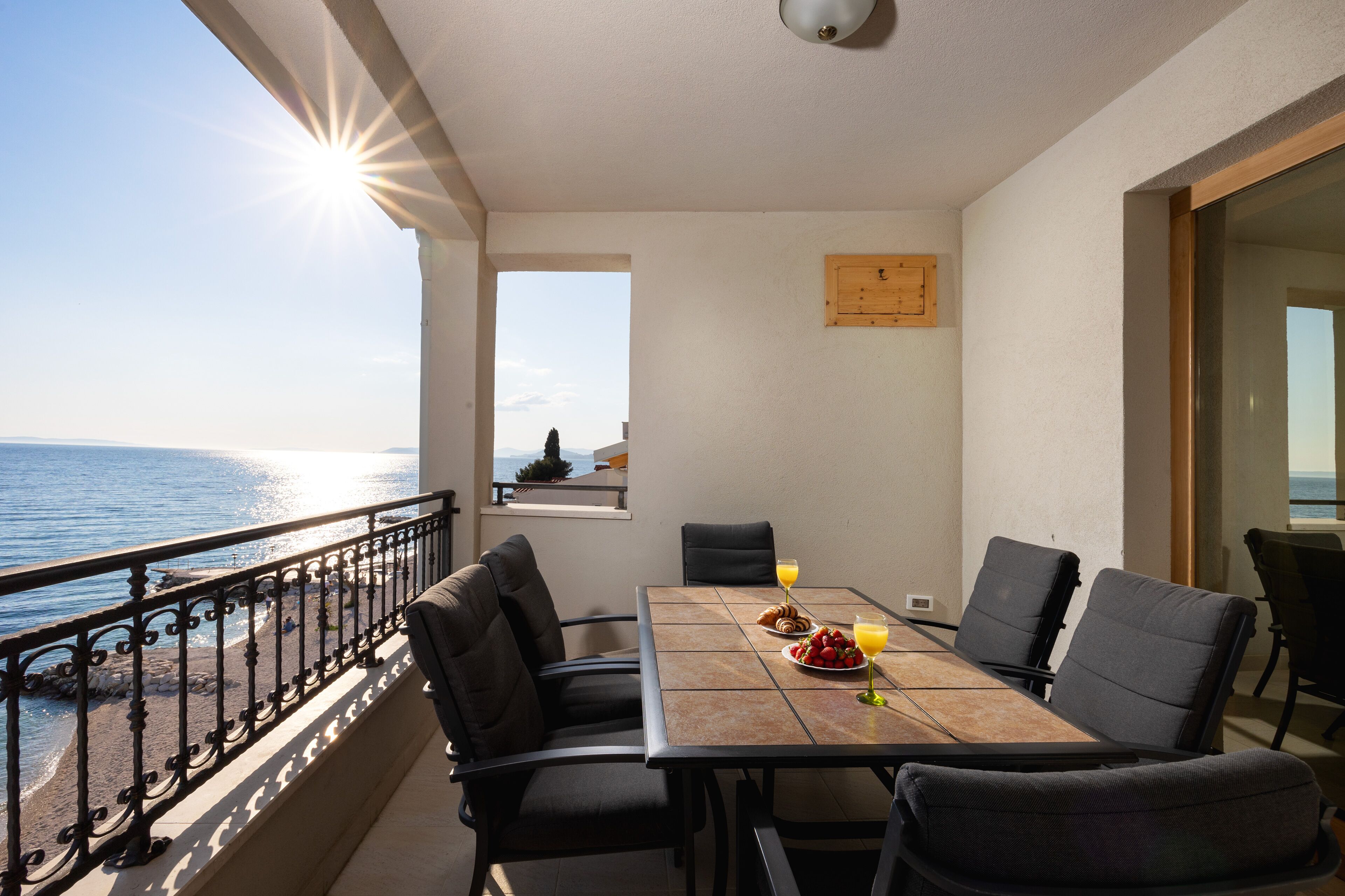 A balcony with a table set for breakfast, overlooking the sea.
