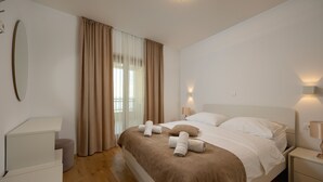 Une chambre d’hôtel avec un lit, des tables de chevet, un miroir et une fenêtre avec des rideaux.