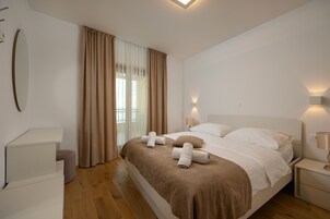 Una habitación de hotel con cama, mesitas de noche, un espejo y un ventanal con cortinas.