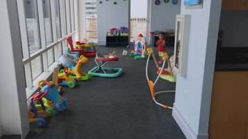 Children can play and learn in this room with a carpeted floor, large windows, and educational materials on the walls.