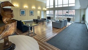 A spacious living room with a large window, a modern sculpture, and a mix of seating options.