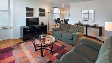 A living room with a sofa, a coffee table, a TV, and artwork on the walls.