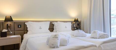 Una habitación de hotel con una cama grande, dos mesitas de noche con lámparas y una ventana con cortinas.
