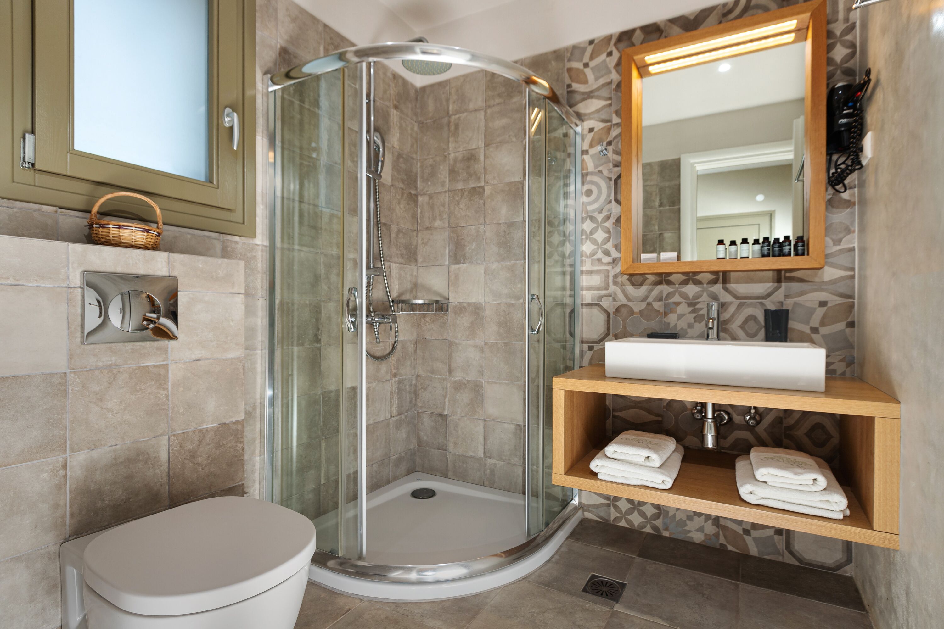 A modern bathroom with a glass-enclosed shower, a toilet, a sink, and a mirror.