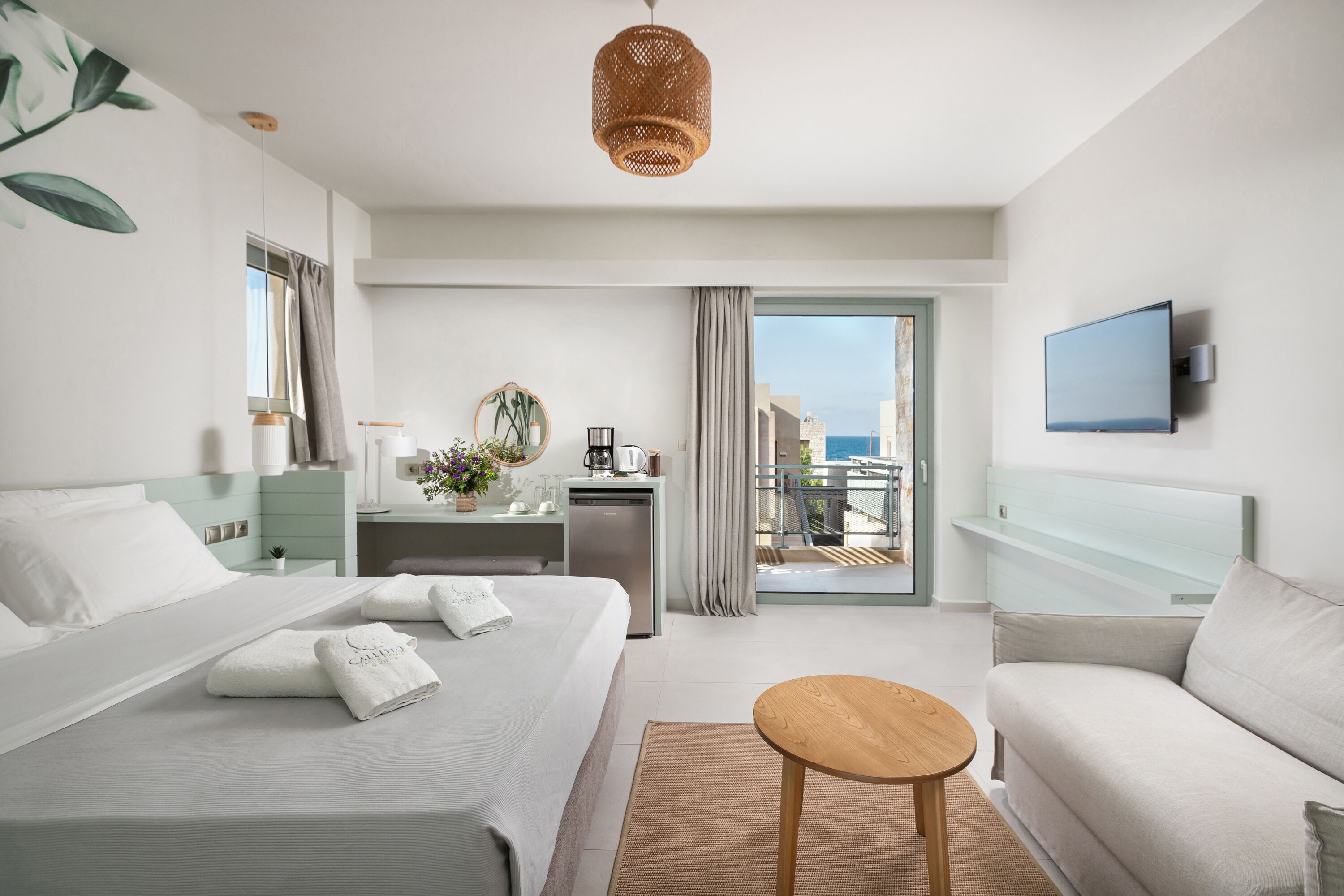 Een moderne hotelkamer met een bed, een bureau, een stoel, een klein tafeltje en een televisie.