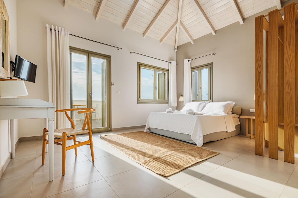 A bedroom with a bed, a desk, a chair, and a TV.