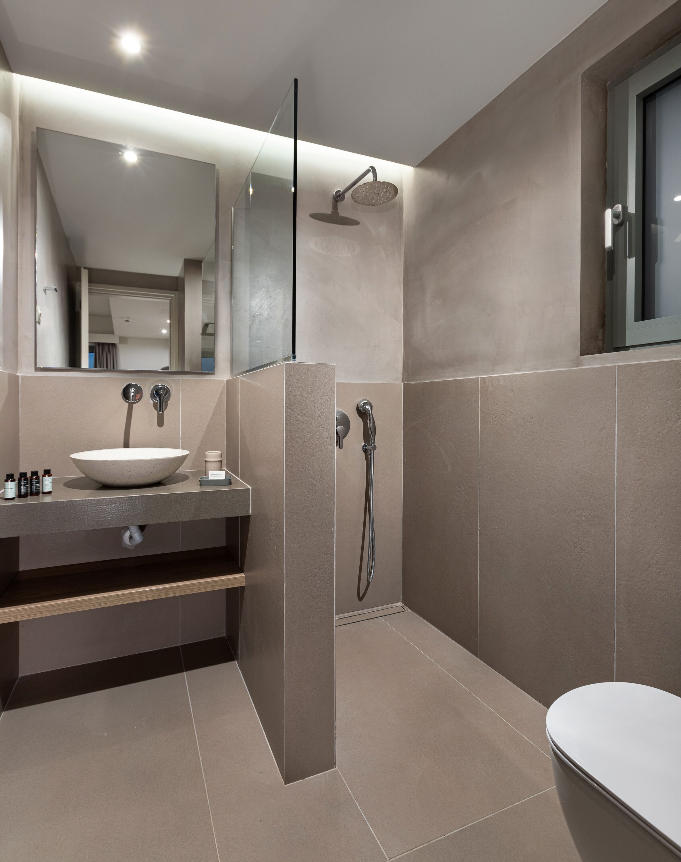 A modern bathroom with a large mirror, a sink, a shower, and a toilet.