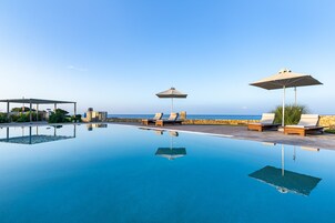 Una piscina al aire libre, sombrillas, sillones reclinables de piscina