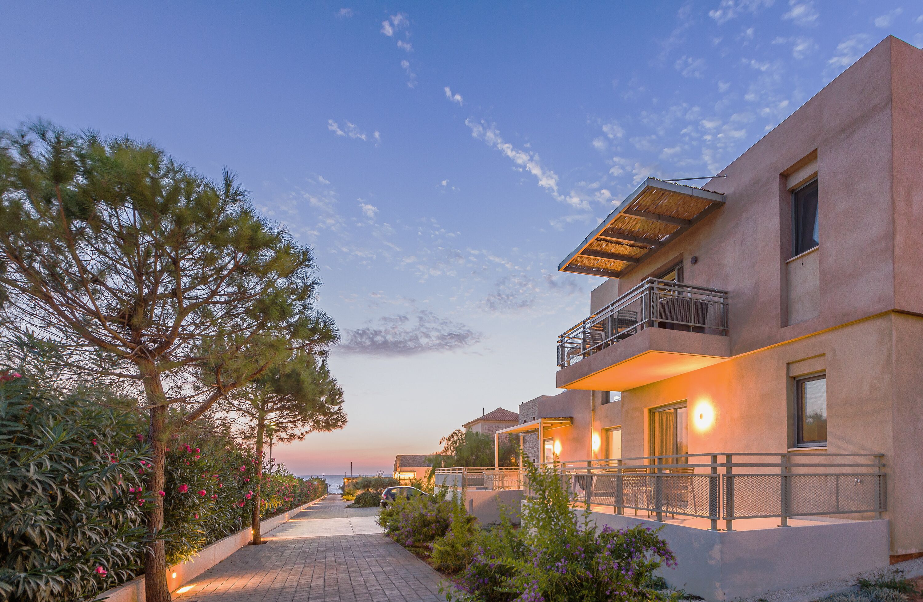 A modern building with a balcony and a pathway leading to the entrance.